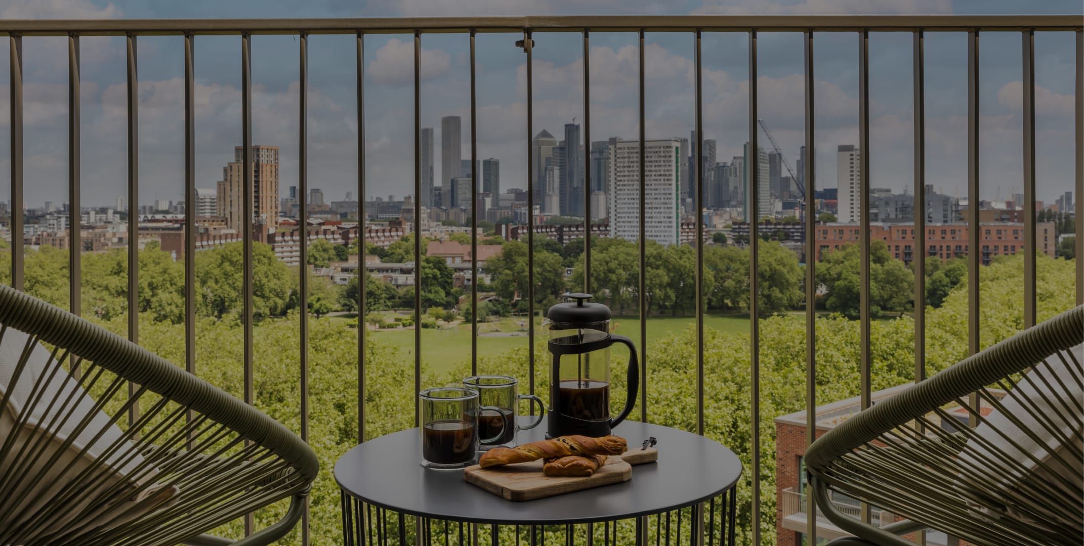 A balcony overlooking Deptford with 2 chairs and a small table.