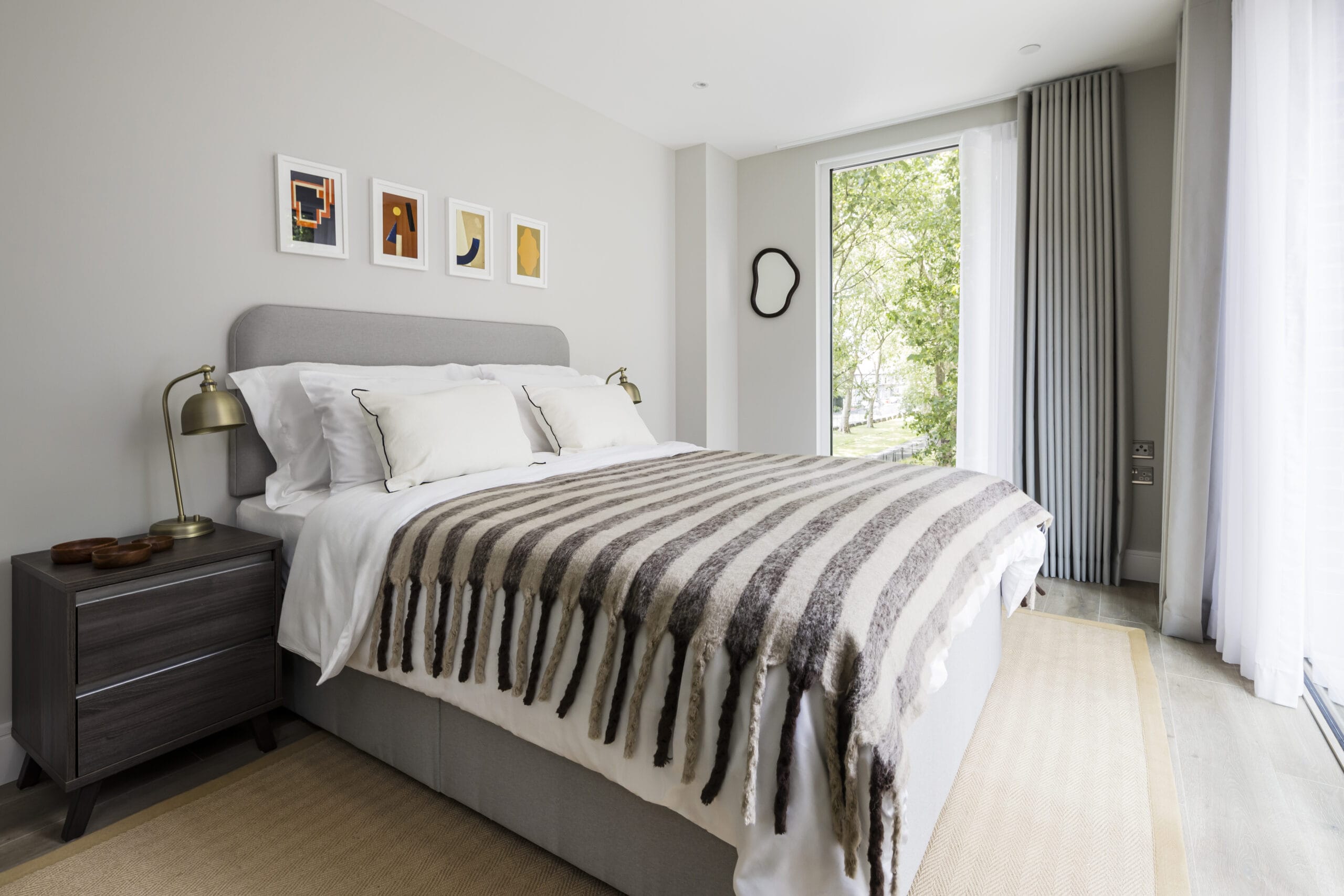 A bright and airy bedroom with floor to ceiling windows, a king size bed and 2 bedside tables.