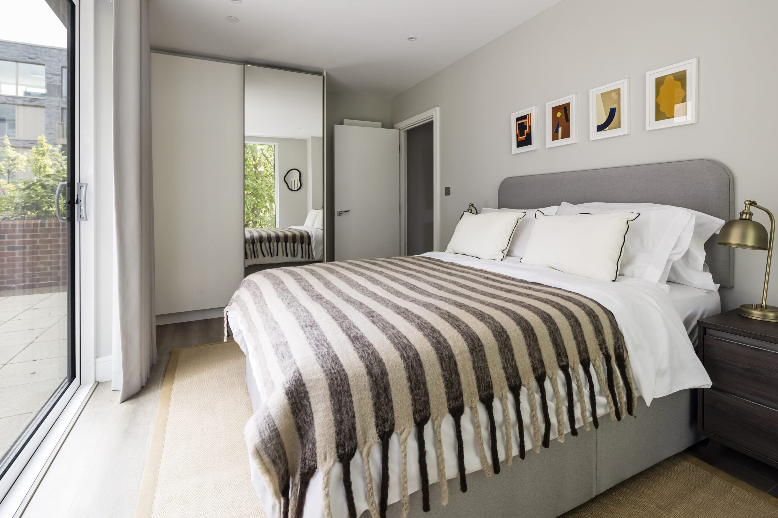 A bright and airy bedroom with a spacious built in wardrobe, a king size bed, 2 bedside tables and a sliding door to access the private outdoor terrace.