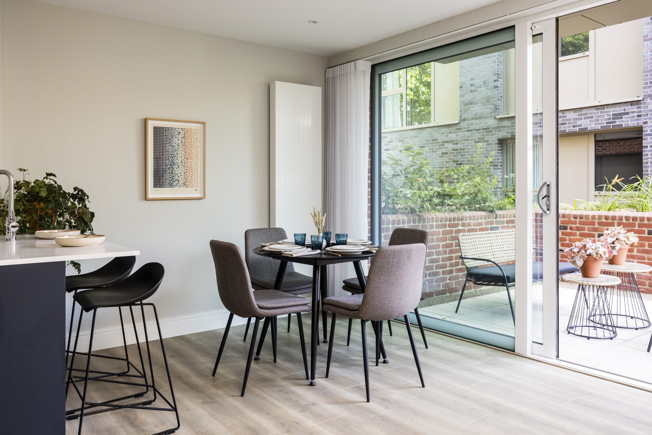 A view of the dining area which leads outside to the private terrace. The table is set for 4 people and the breakfast bar is on the left with 2 stools.