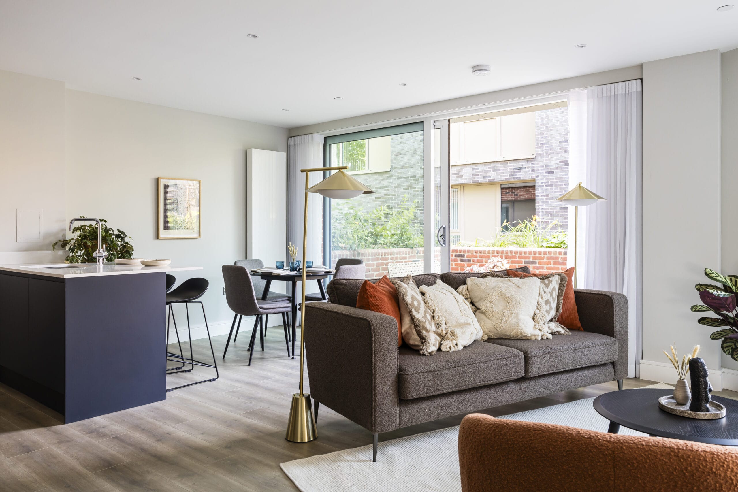 A view of the living/dining area which leads outside to the private terrace. There is a sofa, armchair, coffee table, dining table and breakfast bar.