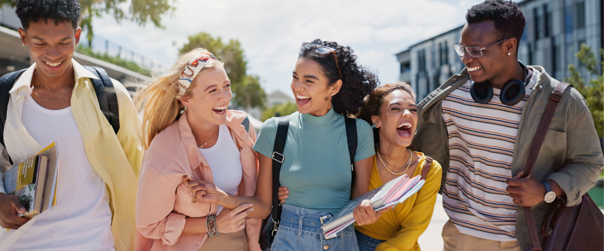 4 students laughing together on campus.