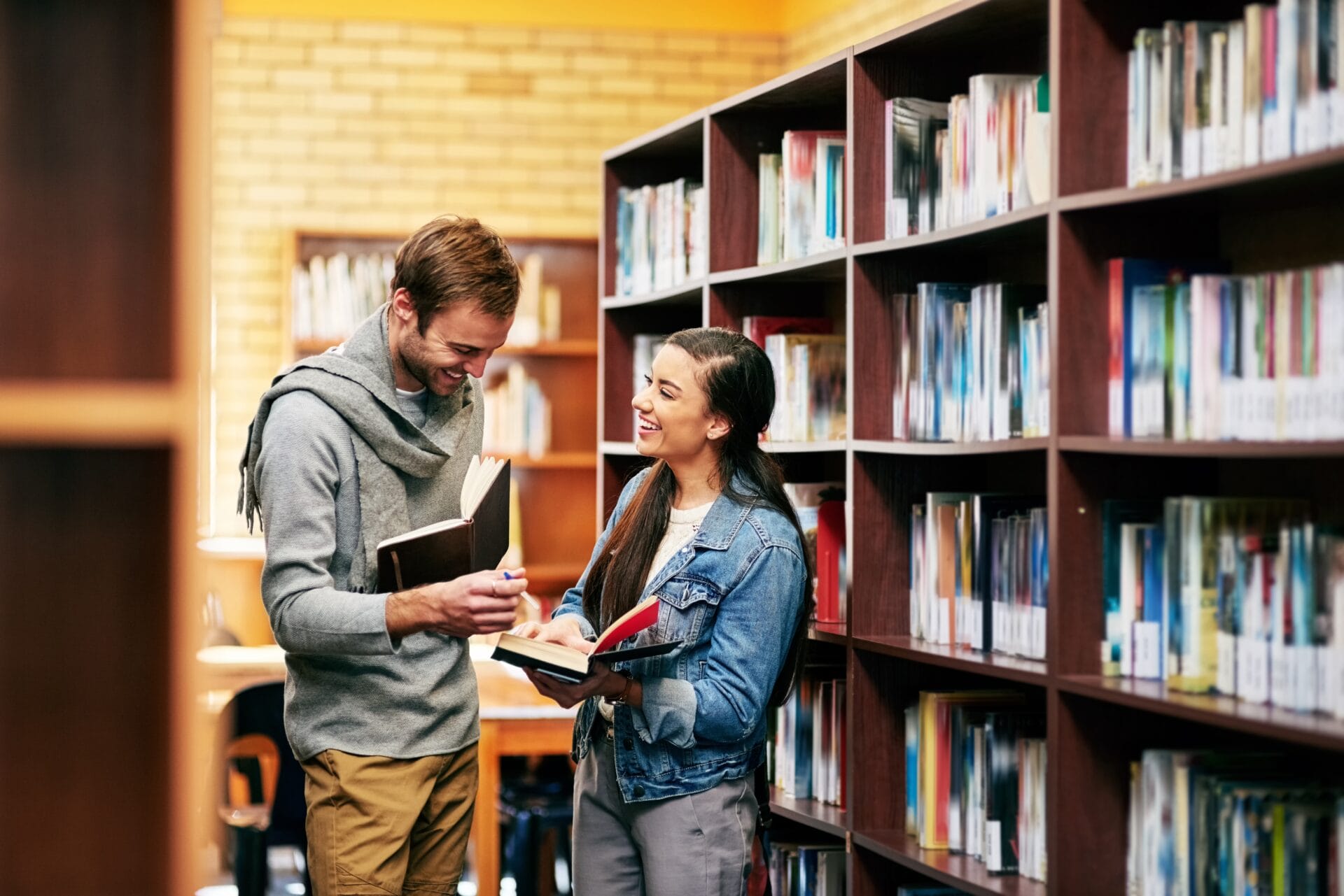 2 young adults smiling together in a university library.