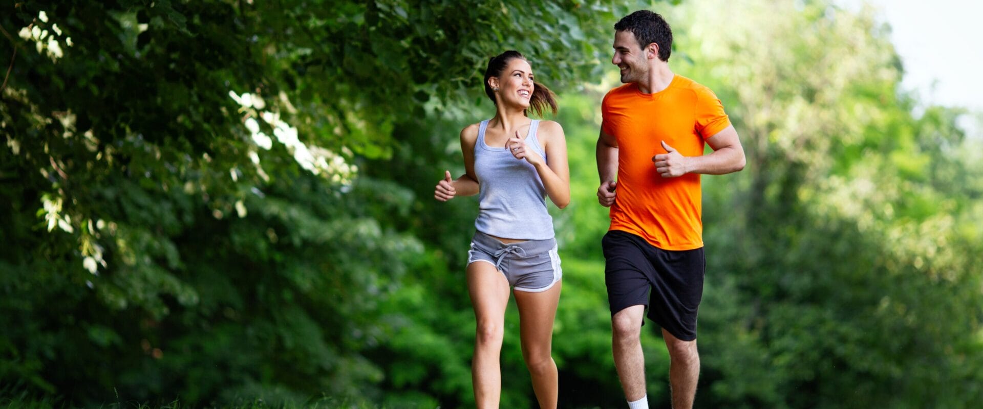 A woman and a man running together in a park.