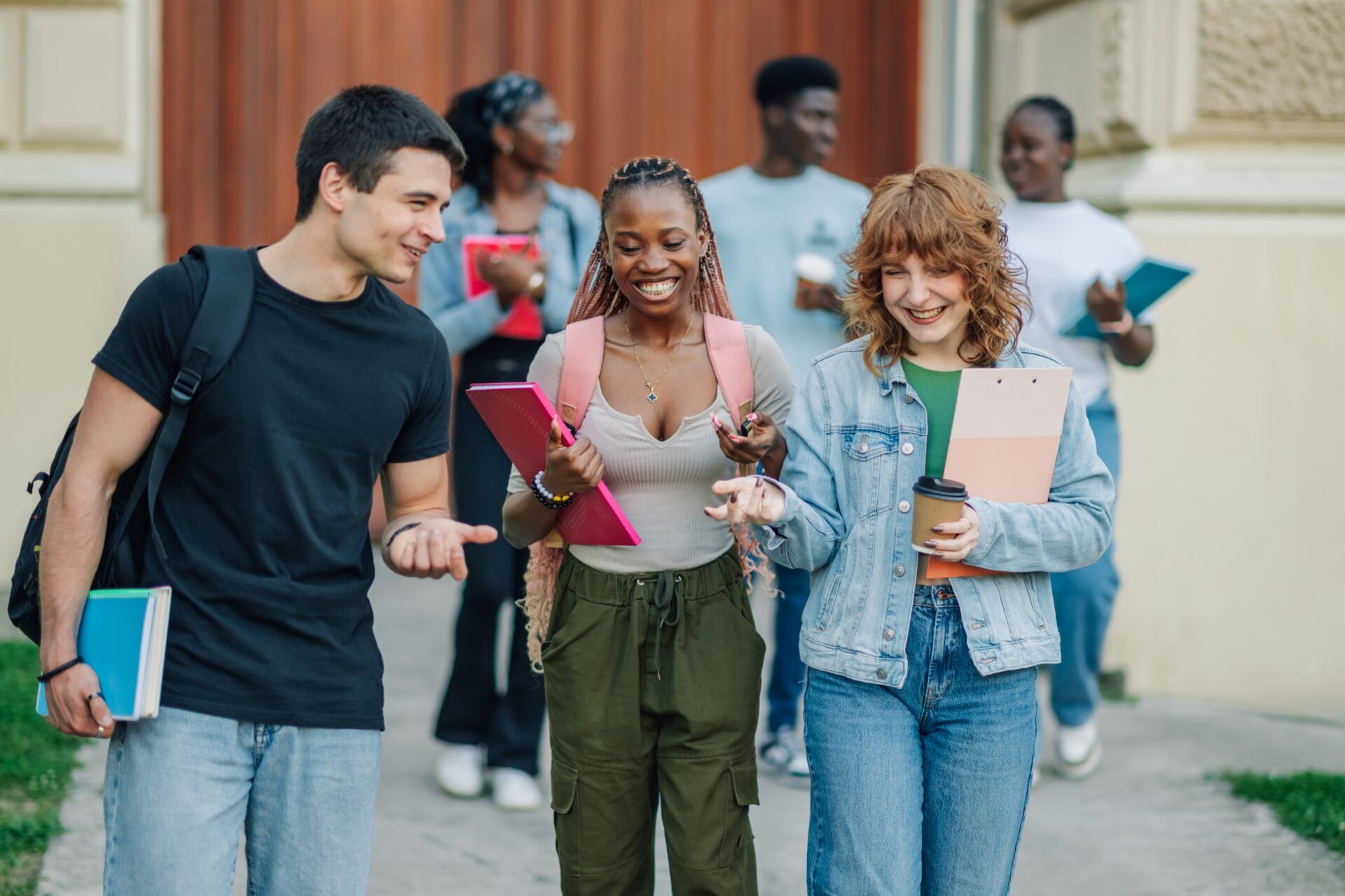 3 college students carrying their notebooks.