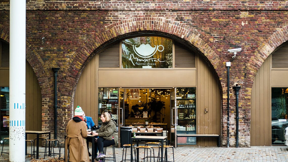 An outdoor shot of the entrance to Mouse Tail Cafe in Deptford. There are 3 people using the outdoor seating.
