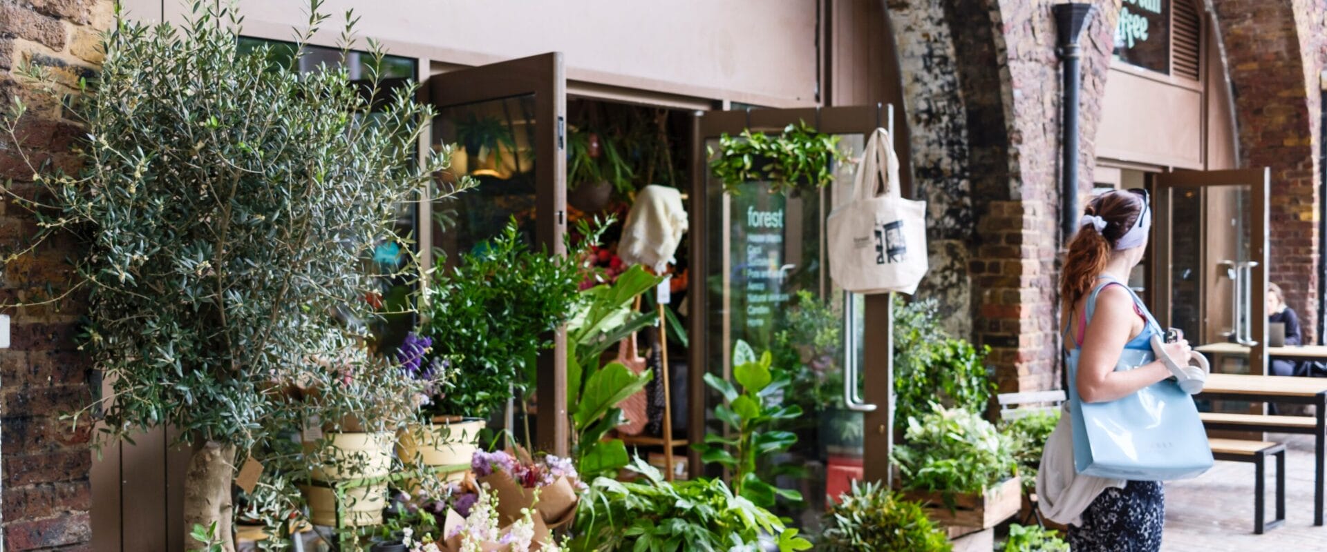 A woman exiting a flower/plant shop on Deptford High Street.