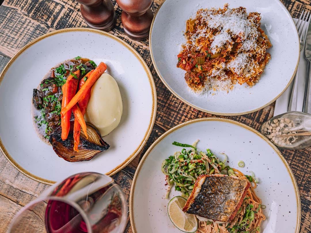 A top down shot of a dining table plated with 3 meals.