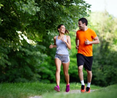 A woman and a man running together in a park.