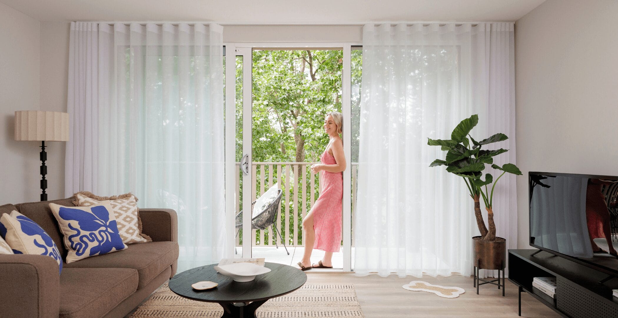A person standing on their balcony in their apartment at Neptune Wharf