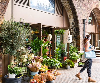 A woman exiting a flower/plant shop on Deptford High Street.